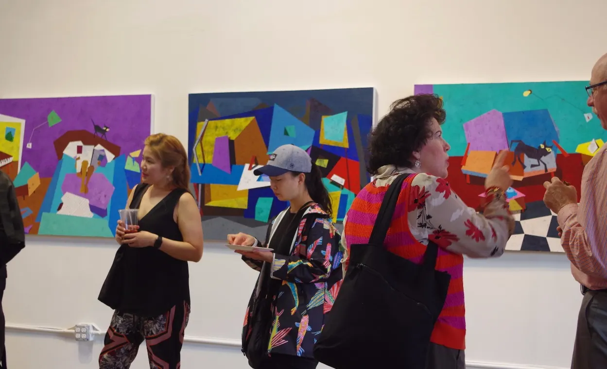 Visitors talking in front of the paintings at an exhibition